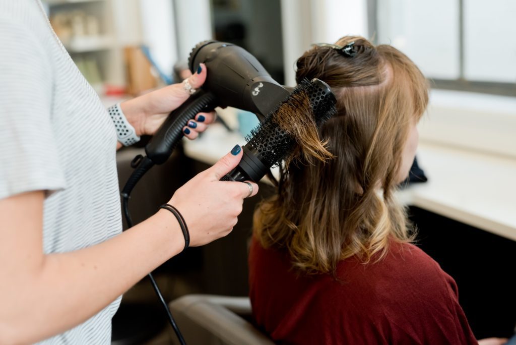 Einer Frau werden in einem Friseursalon die Haare geföhnt.