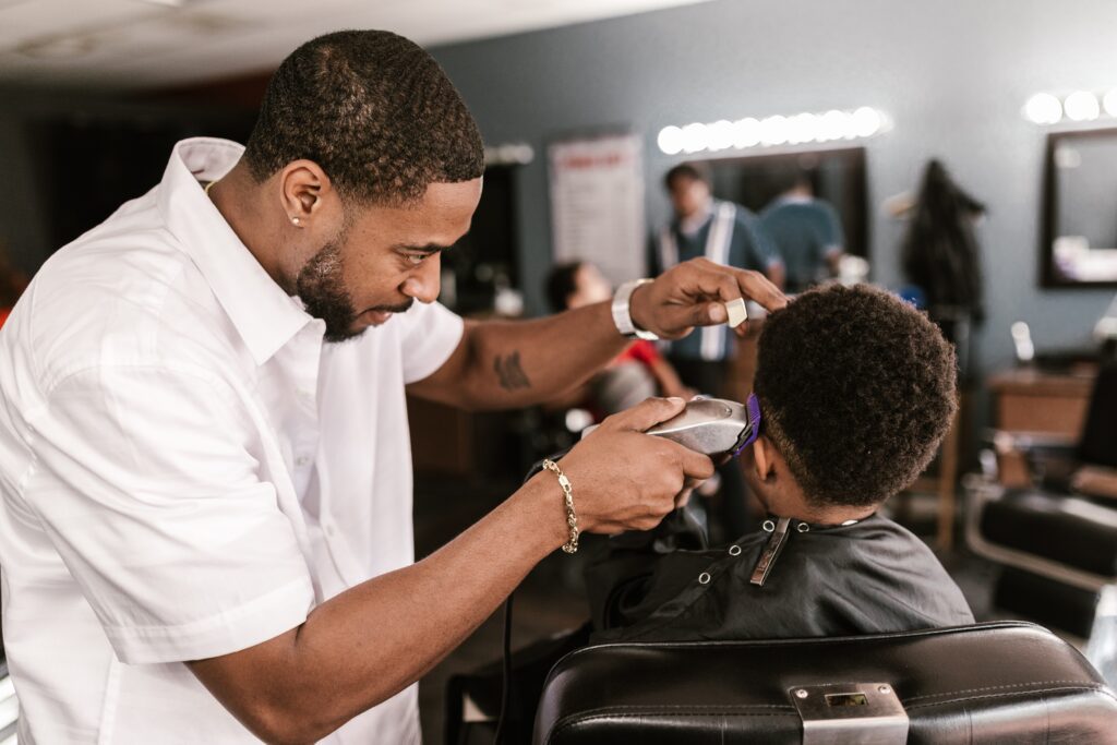 Ein Mann rasiert einem Jungen in einem Barbershop die Haare.