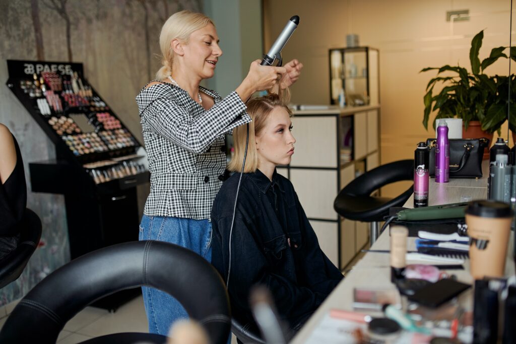 Eine Friseurin lockt einer Kundin die Haare