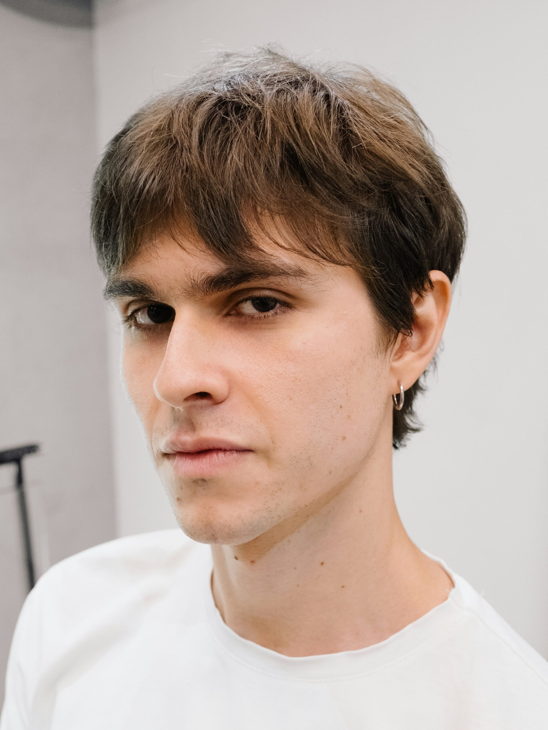 Ein junger Mann mit Business-Vokuhila in einem weien T-Shirt.