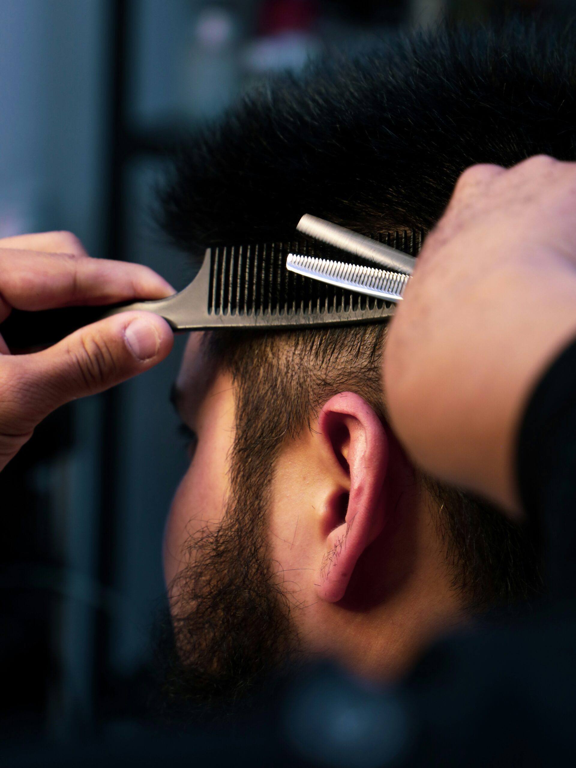 Nahaufnahme eines Barbers, der einem Kunden einen Vokuhila schneidet und sorgfltig die Seiten formt.