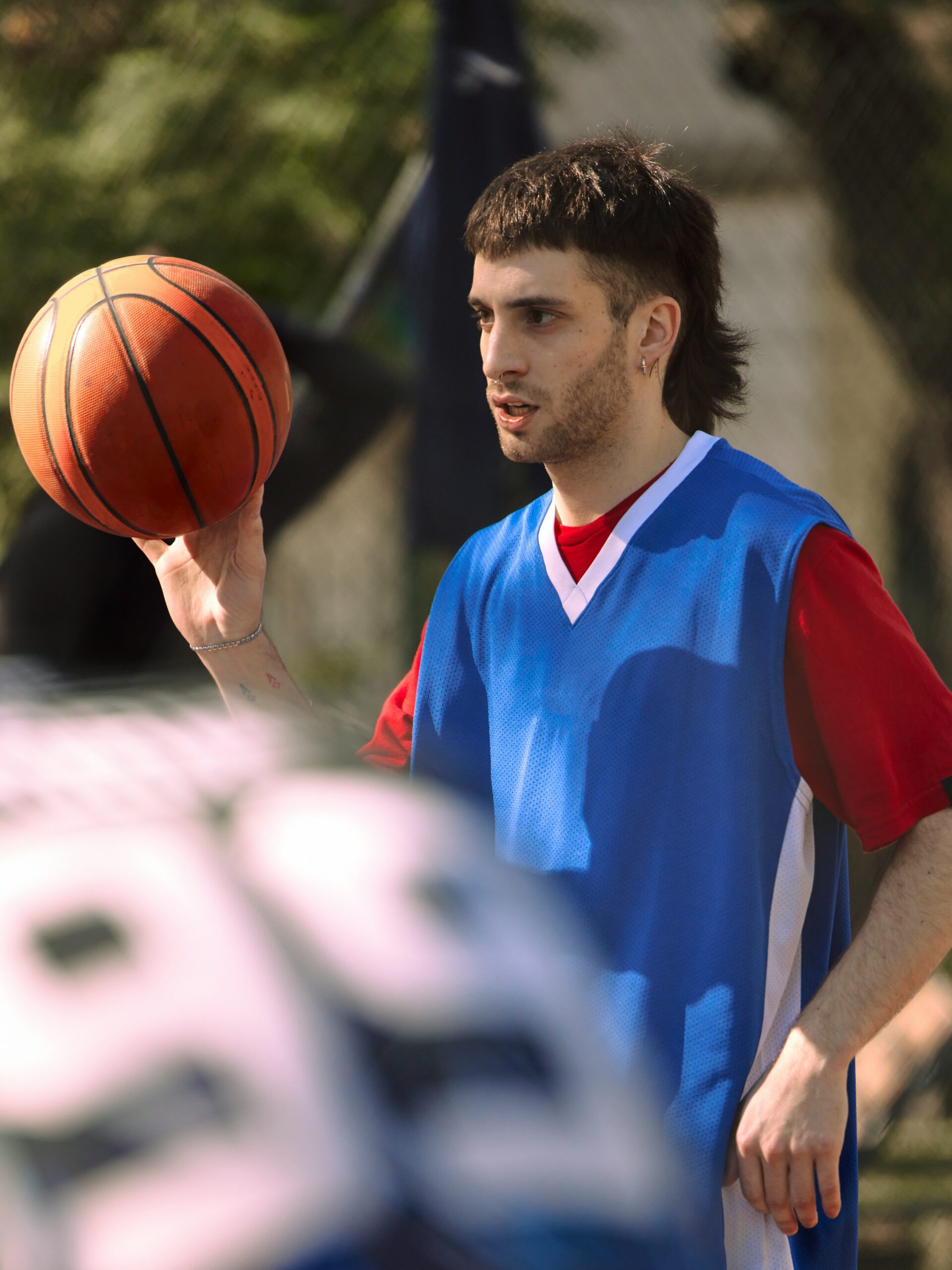 Ein junger Mann mit Fade-Vokuhila beim Basketballspielen.