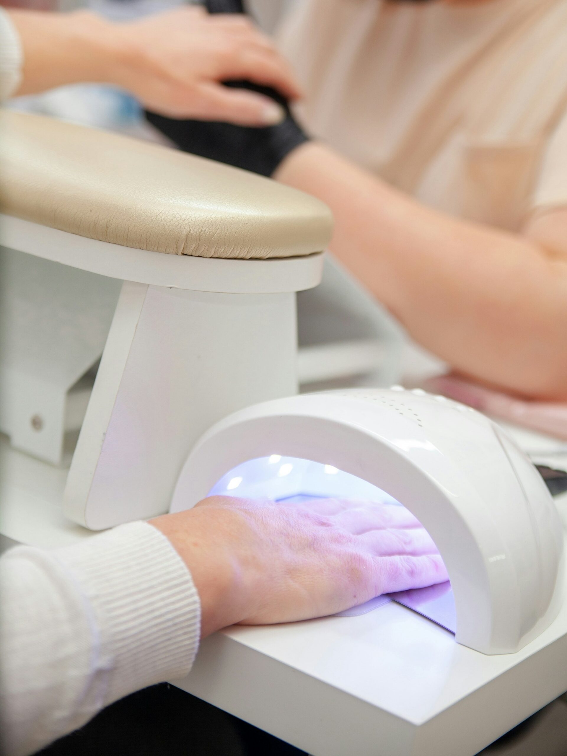 Kundin im Nagelstudio hrtet ihre BIAB-Maniküre unter einer UV-Lampe aus