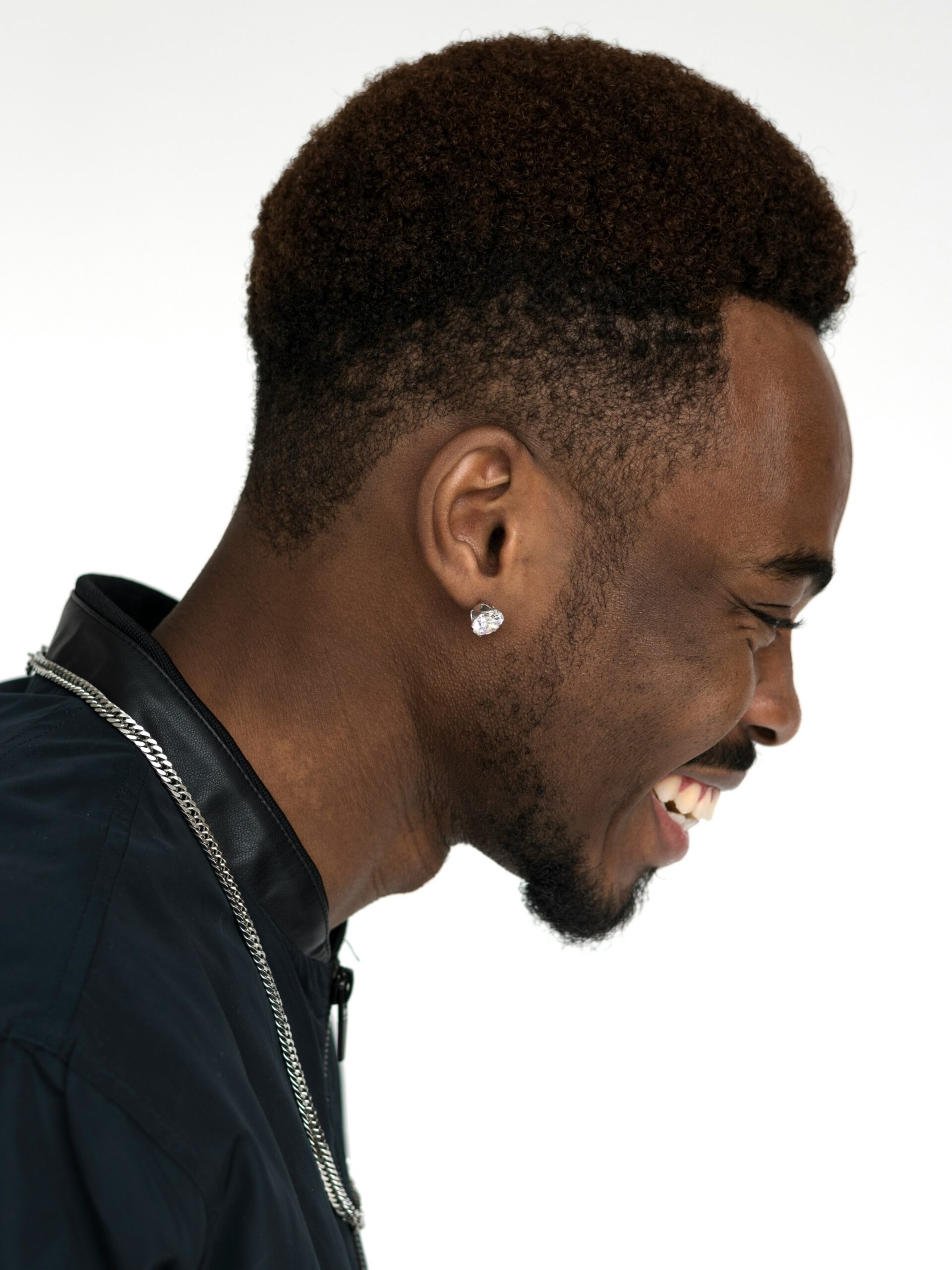 Seitenansicht eines lächelnden Mannes mit Afro-Haar und einem High Taper Fade