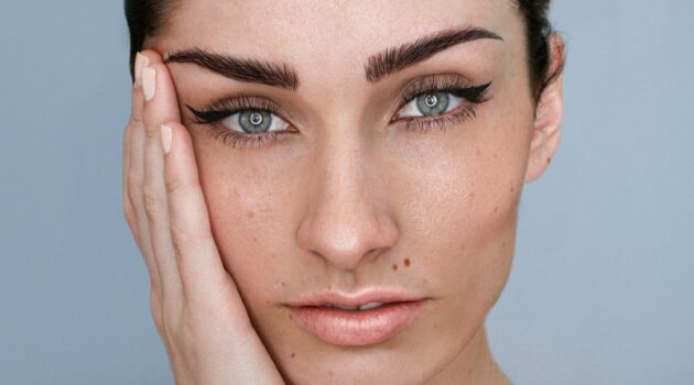 Nahaufnahme des Gesichts einer Frau mit Microblading an den Augenbrauen, natürlichem Make-up und hochgestecktem dunklem Haar