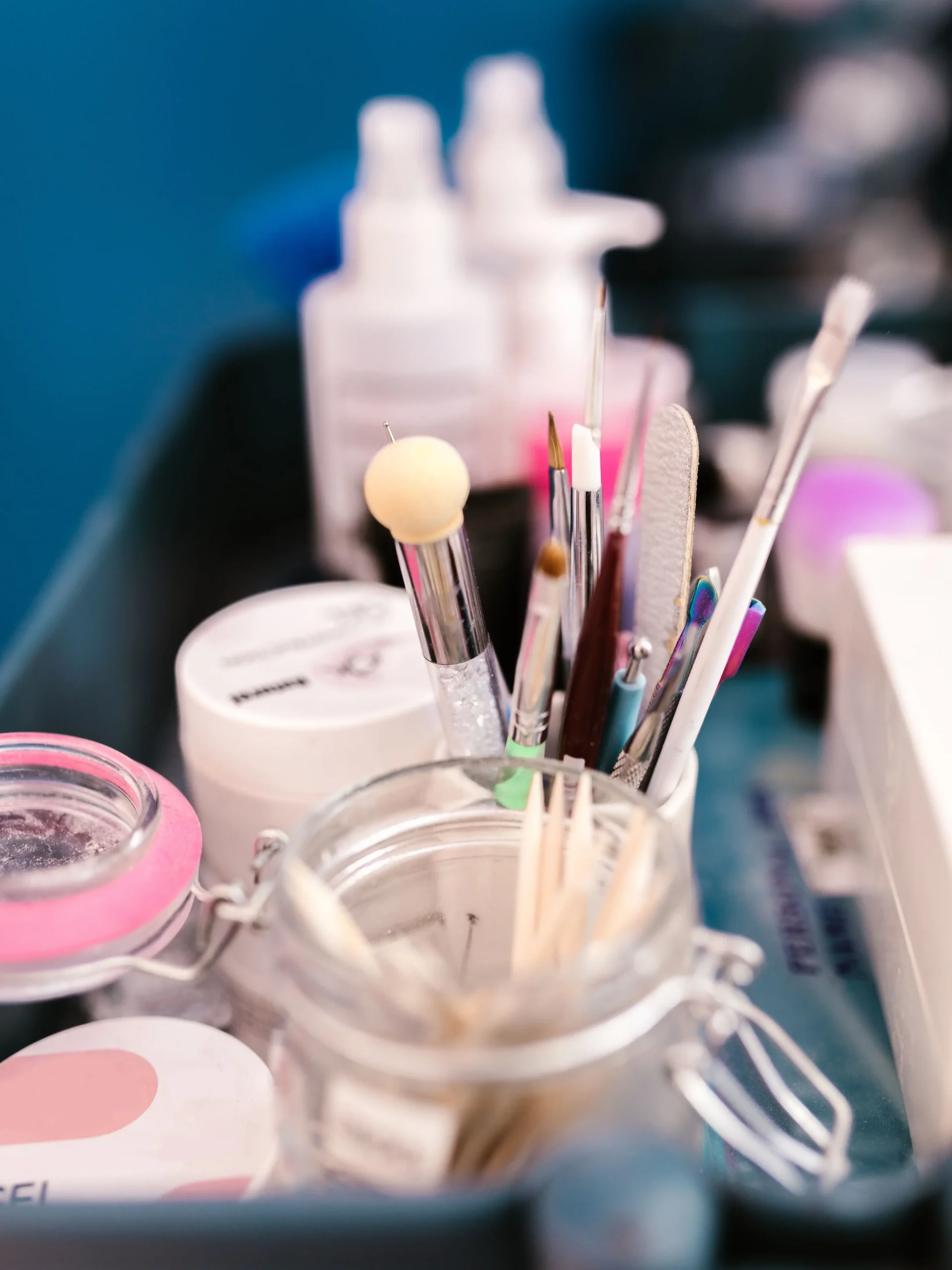 Nahaufnahme des Arbeitsplatzes einer Nageldesignerin im Studio mit Maniküre-Werkzeugen, Pinseln und Produkten