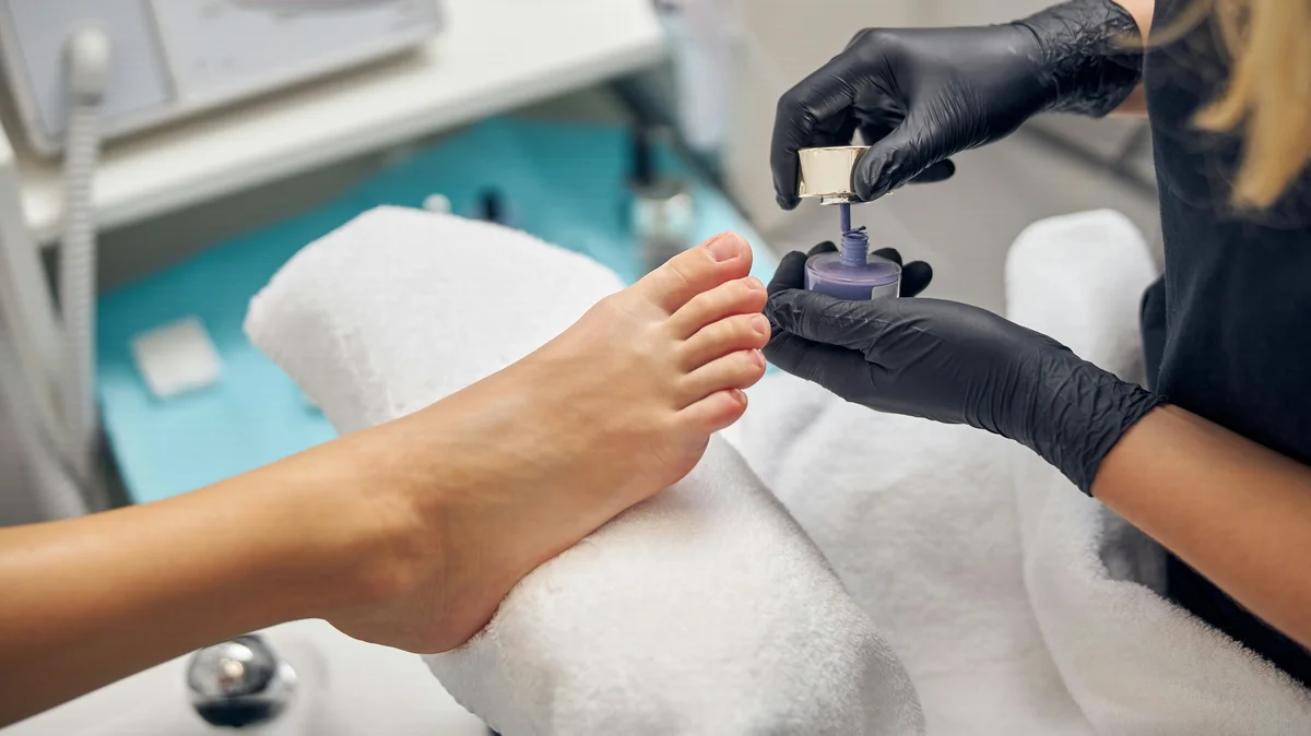 Nahaufnahme einer Nagelstylistin, die einer Kundin im Salon eine Pediküre macht