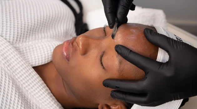 Nahaufnahme einer Kosmetikerin, die bei einer Kundin im Salon ein Dermaplaning durchführt