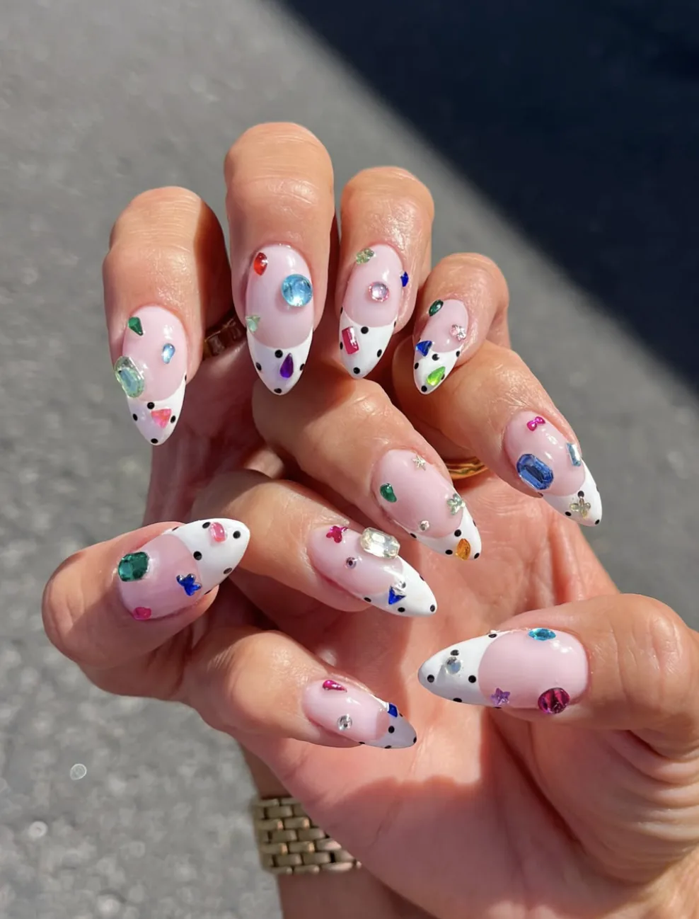 Mandelförmige Bedazzled-Nägel mit bunten Strasssteinen und weißen, gepunkteten Spitzen